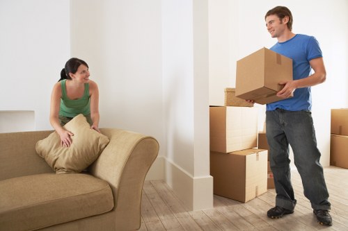 Two movers carrying a sofa down a shared stairwell in a Haringey flat