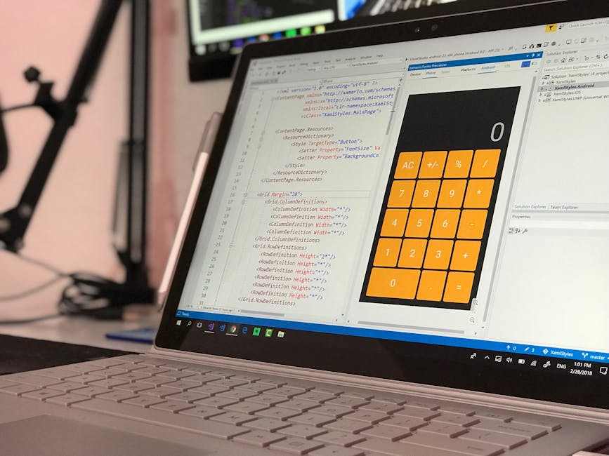 A close-up of a laptop displaying lines of computer code on the left side of the screen and a large, orange calculator interface on the right side, with various arithmetic buttons including plus, minu